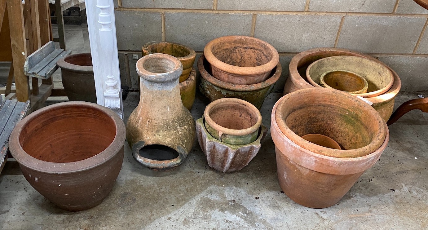 Thirteen assorted circular terracotta planters and a chiminea, largest diameter 51cm, height 31cm